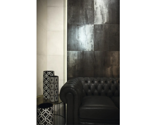 Innenraum mit Wandfliesen in Metalloptik, schwarzem Ledersofa und dekorativen Vasen