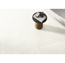 Helle Badezimmerfliese mit kleinem Beistelltisch, Handtuch und Badutensilien neben einer Badewanne