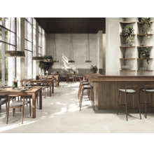 Innenraumansicht eines Restaurants mit Holztischen, Stühlen und einer Bar unter Pendelleuchten