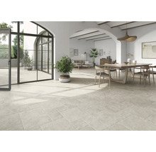 Heller Wohnraum mit Natursteinboden, Esstisch und großen Fenstern.