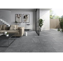 Wohnzimmer mit grauen Bodenfliesen, Sofa, Stehlampe und Gartenzugang