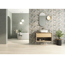 Badezimmer mit Badewanne, Waschtisch, Spiegel und Wandfliesen mit Blattmuster für ein helles, organisiertes Ambiente.