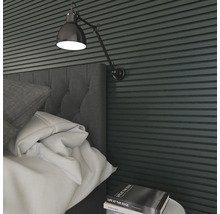 Nahaufnahme eines Schlafzimmers mit Bett, Nachttisch, Buch und Wandleuchte