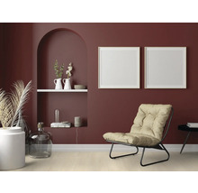 Wohnzimmer mit Sessel, Dekoration und Bilderrahmen an einer bordeauxroten Wand