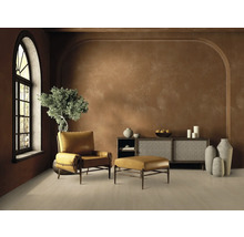 Wohnzimmer mit Sessel, Fußhocker, Sideboard und Dekoration in warmen Erdtönen.