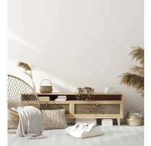 Wohnzimmer mit Rattansessel, Kommode, Kissen und dekorativen Elementen für eine gemütliche Atmosphäre.