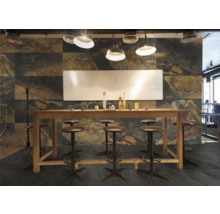 Innenraum mit einer hohen Holztheke, Barhockern und einer Wandverkleidung in Steinoptik.