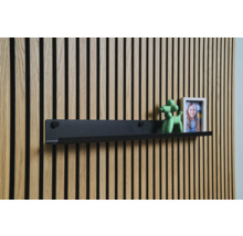 Schwarzes Wandregal vor einer Holzpaneelwand mit Dekoration