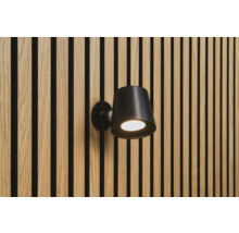 Schwarze Wandleuchte an einer Wand mit Holzpaneelen