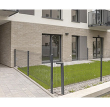 Drahtzaun vor einem modernen Wohngebäude mit Rasenfläche