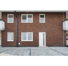 Fassade eines Hauses mit Ziegelmauerwerk, weißen Fenstern und einer Tür