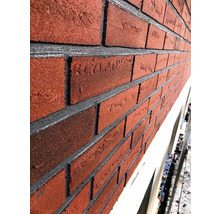 Nahaufnahme einer Fassade mit roten Klinkersteinen und grauen Fugen