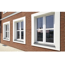 Drei weiße Kunststofffenster in einer Backsteinmauer