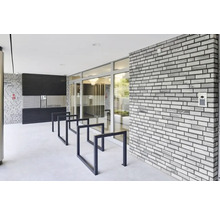 Eingangsbereich eines Wohnhauses mit Briefkästen, Fahrradständer und einer Ziegelwand