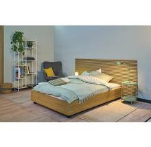 Helles Schlafzimmer mit Holzbett, Nachttischlampe, Regal und Sessel