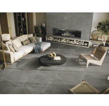 Wohnzimmer mit Sofa, Sesseln, Couchtisch und Kamin mit Holzscheiten auf grauem Steinboden.