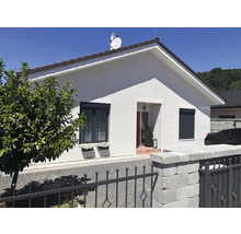 Einfamilienhaus mit weißen Ziegeln, grauen Fensterrahmen und Rollläden