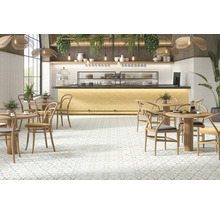 Innenraum eines Cafés mit Tischen, Stühlen und gemusterten Bodenfliesen