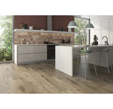 Helle Küche mit Holzboden, Küchenzeile mit Spüle und Kochfeld sowie zwei Barstühlen an einer Küchentheke.