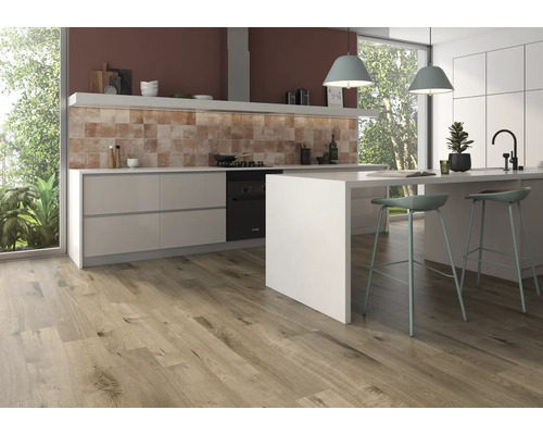 Helle Küche mit Holzboden, Küchenzeile mit Spüle und Kochfeld sowie zwei Barstühlen an einer Küchentheke.