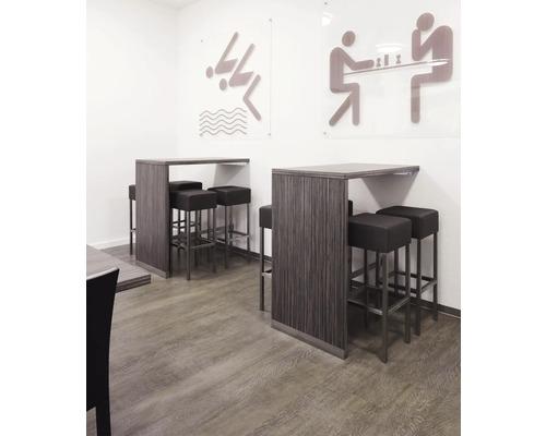 Stehtische mit Barhockern in einem hellen Raum mit Piktogrammen an der Wand