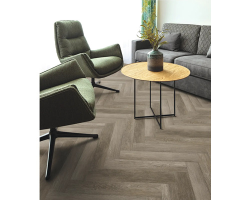 Wohnzimmer mit grauem Sofa, zwei grünen Sesseln und Tisch auf Fischgrätparkett
