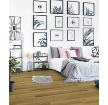 Schlafzimmer mit Holzboden, Bett und dekorativen Bildern an der Wand.