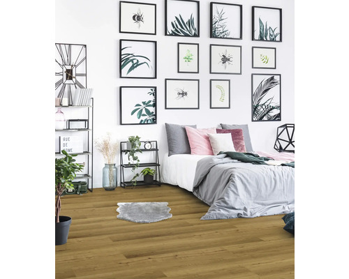 Schlafzimmer mit Holzboden, Bett und dekorativen Bildern an der Wand.