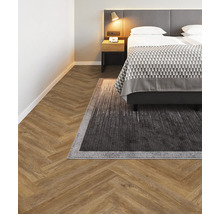 Schlafzimmer mit Fischgrätparkett und Teppich unter dem Bett.