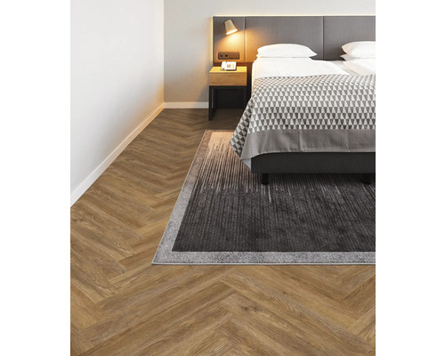 Schlafzimmer mit Fischgrätparkett und Teppich unter dem Bett.