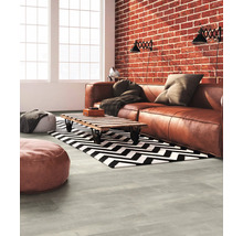 Wohnzimmer mit Ledersofa, Couchtisch, Teppich mit Zickzackmuster und Ziegelwand