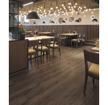 Gastraum mit Holzboden, Tischen und Stühlen unter dekorativer Beleuchtung.