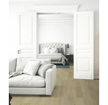 Wohnzimmer mit Sofa und Blick auf ein Schlafzimmer mit Bett