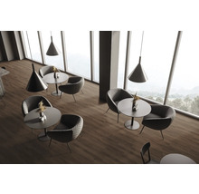 Innenraum mit Sitzgruppen, bestehend aus Tischen und Sesseln, beleuchtet durch Pendelleuchten