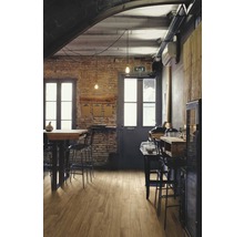 Gastraum mit Holzboden, Tischen, Stühlen und Backsteinwand