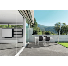 Terrasse mit Fliesenboden, Tisch und Stühlen im Außenbereich.