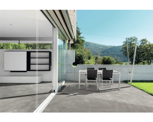 Terrasse mit Fliesenboden, Tisch und Stühlen im Außenbereich.