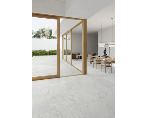 Heller Raum mit Fliesenboden, Esstisch und Blick in den Garten