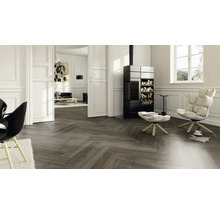 Wohnzimmer mit Fischgrätenparkett, Kaminofen und Sesseln für eine gemütliche Atmosphäre.