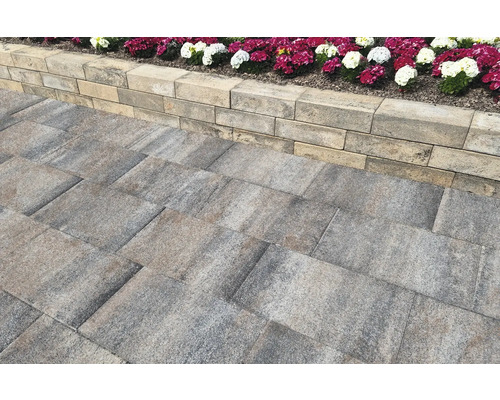 Gepflasterter Weg mit Mauer und Blumenbeet