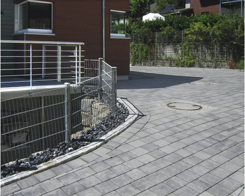 Außenansicht mit Pflastersteinen, Zäunen und Bepflanzung