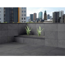 Terrasse mit Fliesen und Pflanzenkübel vor dem Hintergrund einer Stadtlandschaft.