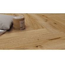 Verlegung von hellem Parkett im Fischgrätmuster mit Kissen und Kerze