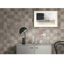 Wandgestaltung mit quadratischen Fliesen über einem Sideboard mit Lampe und Dekoration