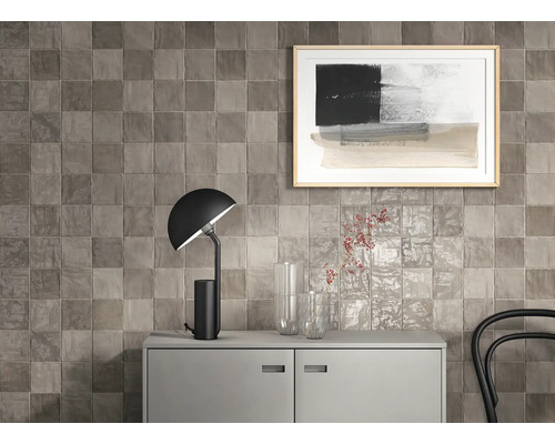 Wandgestaltung mit quadratischen Fliesen über einem Sideboard mit Lampe und Dekoration