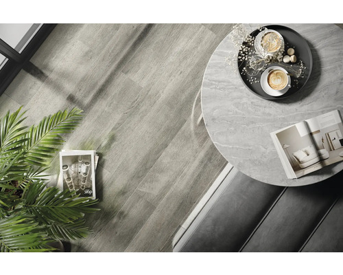 Innenaufnahme eines Raumes mit Holzboden, einem runden Tisch mit Marmorplatte und Dekorationen.