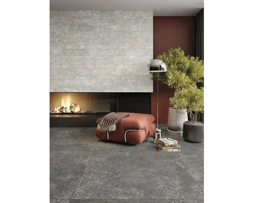 Wohnzimmer mit Kamin, Steinfliesenwand und grauem Boden