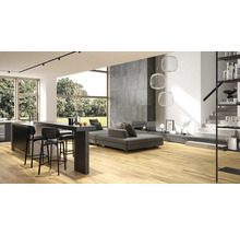 Helles Wohnzimmer mit Holzboden, grauer Couch, Küchenbar und Treppe