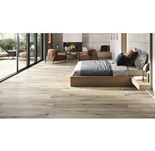 Heller, offener Wohnraum mit Holzbodenfliesen, Bett, Kamin und Sitzbereich im Freien