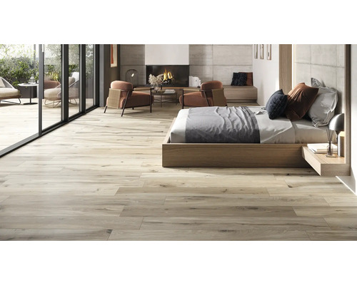 Heller, offener Wohnraum mit Holzbodenfliesen, Bett, Kamin und Sitzbereich im Freien